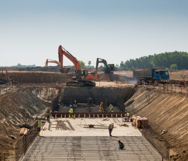 A close shot of heavy machines and construction workers working on a building
